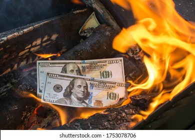 Two Hundred Dollar Bills Are Burning In The Fire, Symbolizing The Recession Of The Economy, Crisis, Confusion, Misfortune, Poverty. Depreciation Of Money. Burning Excess Money. Excessive Rust.