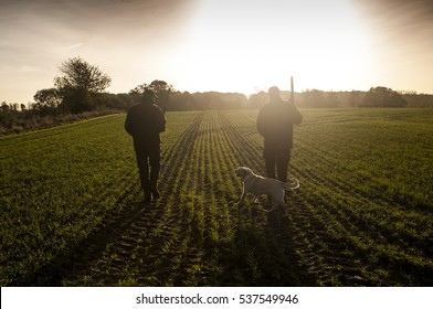 Two hunters and a hunting dog on a field