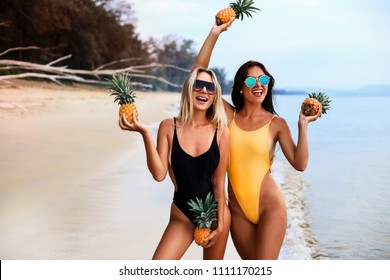 two incredibly beautiful sexy girl models in a bikini on the sea shore of a tropical island, blonde brunette, bronze tan, travel summer vacation, fashion style