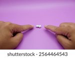 two index fingers are pointing at house lizard eggs on a purple background