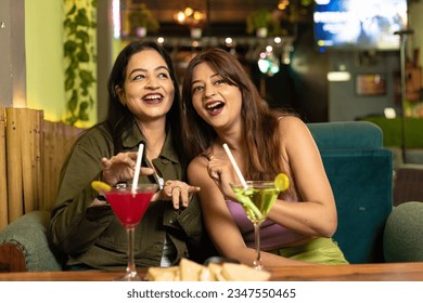 Two indian female friends discussing, laughing and enjoying party together at restaurant. - Shutterstock ID 2347550465