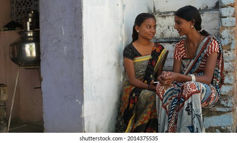 Two Indian Girls In Traditional Clothes Sitting Outdoor And Talking