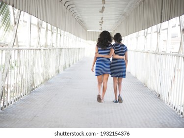 Two Indian Girls Walking On The Street Holding Each Other. Back View Of Teenage Girl Best Friends. 