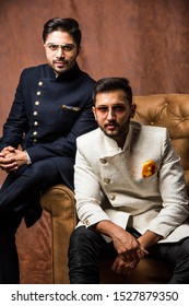 Two Indian Men Wears Ethnic Or Traditional Cloths,  Male Fashion Models With Sherwani Or Kurta Pyjama, Sitting And Posing On Wing Chair Or Sofa Against Brown Grunge Background, Selective Focus