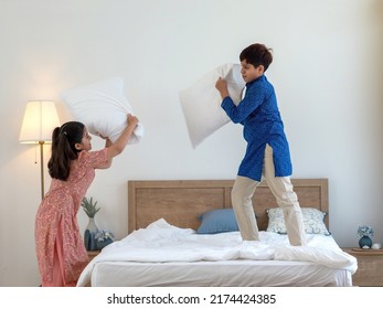 Two Indian sibling, brother and sister wearing traditional clothes having fun time pillow fighting in bedroom at home or apartment. Play time with love and bonding together. Family concept. - Shutterstock ID 2174424385
