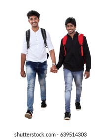 Two Indian students walking in to the camera angle  along with their backpack.
