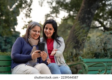 Two indian woman in warm wear and talking on video call at park. - Powered by Shutterstock