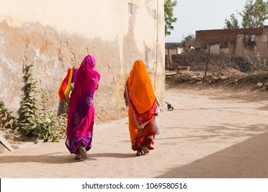 Two Indian Women With Colorful Traditional Dresses, Walking Along The Brick Road.