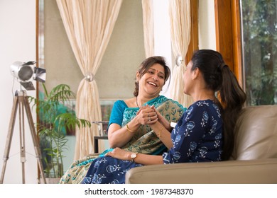 Two Indian Women Sitting On Sofa At Living Home