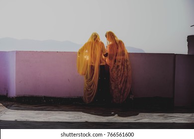Two indian women in yellow saris facing mountains in Pushkar, India - Powered by Shutterstock