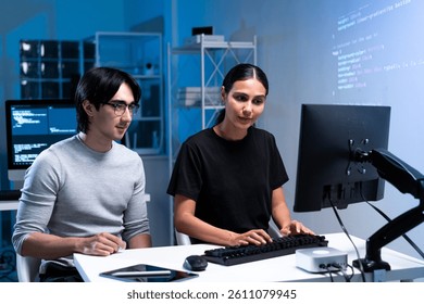 Two individuals collaborate on coding in a modern workspace, focused on computer screens with programming code in the background. - Powered by Shutterstock - Get 15% off with code: PIKWIZARD15