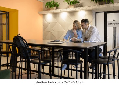 Two individuals collaborating on documents in a professional modern coworking environment.