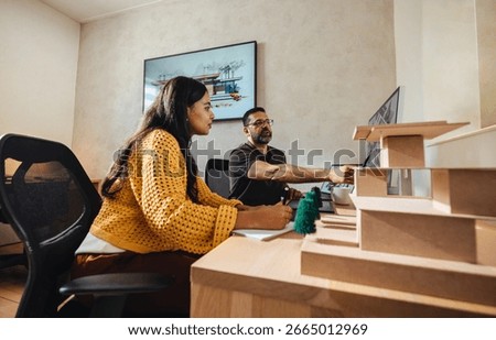 Two individuals engaged in a collaborative project in a bright office, representing a modern and focused architecture firm setting with minimalist elements and creative teamwork.