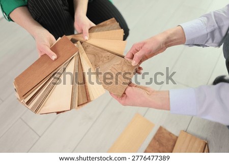 Two individuals are engaged in selecting various wood samples, highlighting their textures and colors in a well-lit space filled with warm design elements.