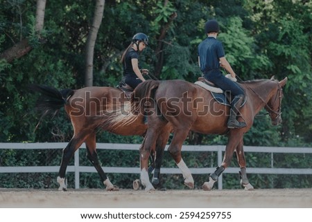 Two individuals enjoy horseback riding through a lush green area, showcasing skill and companionship with the horses. The scene exudes tranquility and connection with nature.