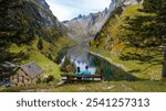 Two individuals enjoy a peaceful moment atop a hillside, overlooking the stunning Falensee in Appenzell, Switzerland. The vibrant autumn colors create a breathtaking landscape harmony.