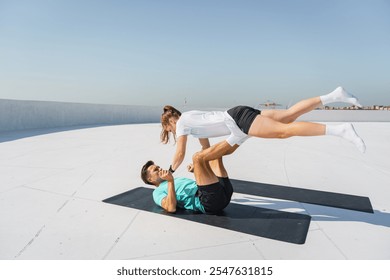 Two Individuals Practice Acrobatic Yoga on a Rooftop Overlooking the Ocean on a Clear Day - Powered by Shutterstock