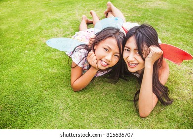 two indonesian sisters lying down on a grass - Powered by Shutterstock