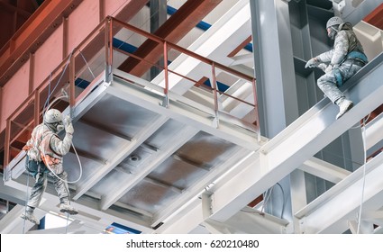 Two Industrial Climbers Paint The Metal Frame Of A Power Plant Under Construction