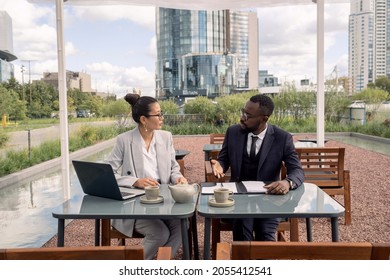 Two Intercultural Business Partners Discussing Terms Of Contract Before Signing It