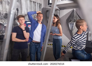 Two Interested Teen Boys With Their Parents Trying To Get Out Of Closed Space Of Escape Room Stylized Under Abandoned Nuclear Bunker, Contemplating Solving Conundrums..