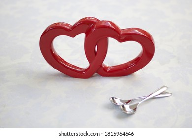 Two intertwined red hearts and a pair of silver teaspoons