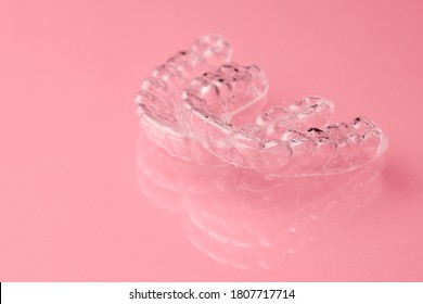 Two Invisible dental teeth aligners on the pink background. Orthodontic temporary removable braces for fixing teeth after alignment. Therapy after brackets. 