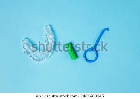 Two invisible removable aligners and accessory tools on the blue background. Orthodontic treatment