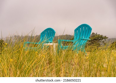 Two Isolated Empty Blue Chairs For Sitting And Relaxing While Looking Out On The Ocean Shore.