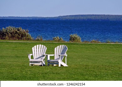 Two, Isolated, White Adirondack Chairs Against Lake Background