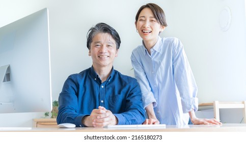 Two Japanese Men And Women Talking In Front Of A Computer