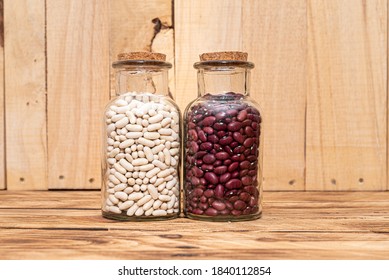 Two Jars Of Dried Beans. Red Kidney Beans And White Beans, Dried For Preservation And Long Term Storage On Natural Wooden Background.