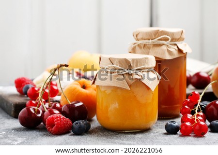 Two jars with peach jam and fresh fruits on stone background.  商業照片 © 