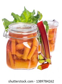 two jars with rhubarb compote and rhubarb leaf on white background