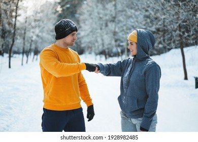 Two Joggers Greeting Each Other With A Fist Bump Gesture During Winter Workout Outside