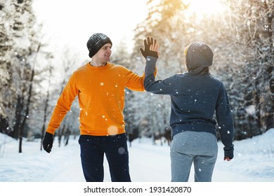 Two Joggers Greeting Each Other With A High Five Gesture During Winter Workout Outside