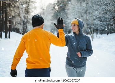 Two Joggers Greeting Each Other With A High Five Gesture During Winter Workout Outside