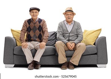 Two Joyful Elderly Men Sitting On A Sofa Isolated On White Background