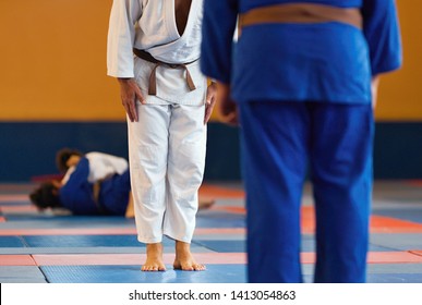 Two judo fighters or athletes greeting each other in a bow before practicing martial arts in the background of the ongoing match - Powered by Shutterstock