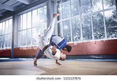 Two judo fighters showing technical skill while practicing martial arts in a fight club. The two fit men in uniform. fight, karate, training, arts, athlete, competition concept
