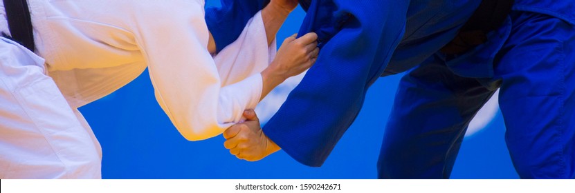 Two judo fighters in white and blue uniform. Martial arts competition - sambo, judo, karate, jiu jitsu, wrestling