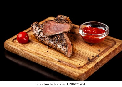 Two Juicy Beef Pepper Steak With A Air Fryer Medium Rare, With A Red Sharp Sauce On A Wooden Board, On A Black Background. Copy Space