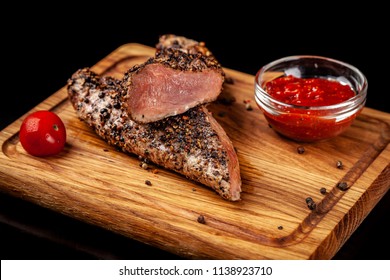 Two Juicy Beef Pepper Steak With A Air Fryer Medium Rare, With A Red Sharp Sauce On A Wooden Board, On A Black Background. Copy Space