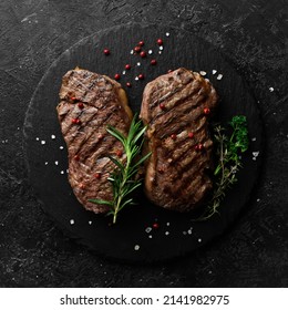Two juicy rib eye steak, herbs and spices. On a black stone background. - Shutterstock ID 2141982975