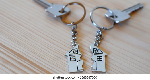 Two keys with splitted broken key rings with pendant in shape of house divided in two parts on wooden background with copy space. Dividing house at divorce, division of property real estate heritage. - Shutterstock ID 1368587300