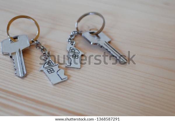 Two keys with splitted broken key rings with
pendant in shape of house divided in two parts on wooden background
with copy space. Dividing house at divorce, division of property
real estate heritage.