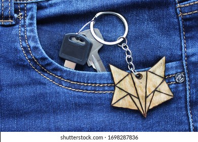 Two keys with wooden fox-shaped keychain in jeans pocket 