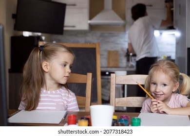 Two Kid Girls Drawing. Parents Cooking. Virtual Classes At Home. Remote Drawing Lesson. Painting. Children, Sisters, Siblings. Creative Hobby, Family Leisure Activity. Learning Remotely In Quarantine