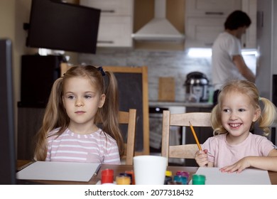 Two Kid Girls Drawing. Parents Cooking. Virtual Classes At Home. Remote Drawing Lesson. Painting. Children, Sisters, Siblings. Creative Hobby, Family Leisure Activity. Learning Remotely In Quarantine