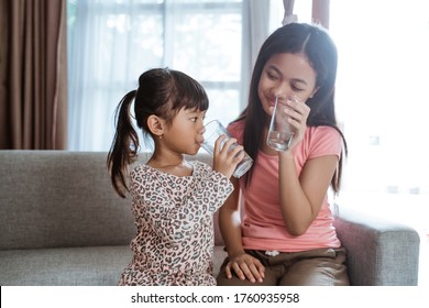 Two Kid Sibling Sister Having A Glass Of Water To Drink At Home